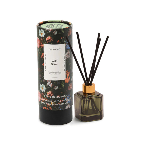 The Botanical Diffuser Set features a floral pattern, a decorative cylindrical box, and a square glass bottle with black reeds in a gold-colored cap.