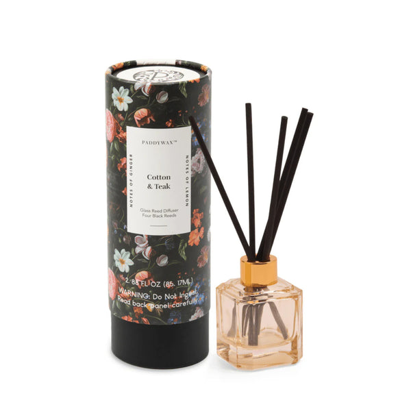 The Botanical Diffuser Set features a floral-patterned Cotton & Teak tube beside a reed diffuser bottle with black sticks, providing an elegant way to enhance your home's fragrance.