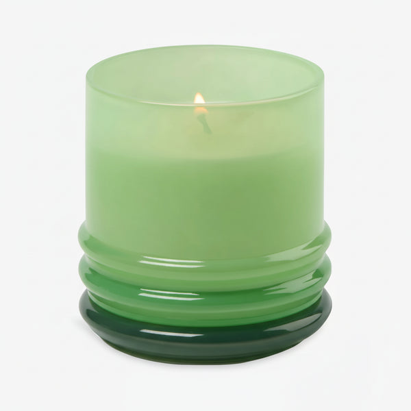 The 7oz Stacked Glass Candle, crafted from green soy wax, glows in a glossy translucent green glass holder with a ribbed base, set against a plain white background.